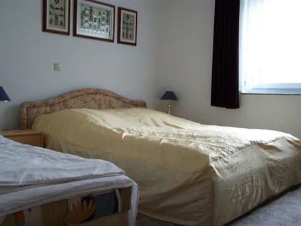 Schlafzimmer mit Doppelbett und separater Liege.