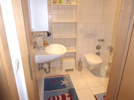 Badezimmer mit Dusche, Fußbodenheizung, großem Regal und Handtuchtrockner