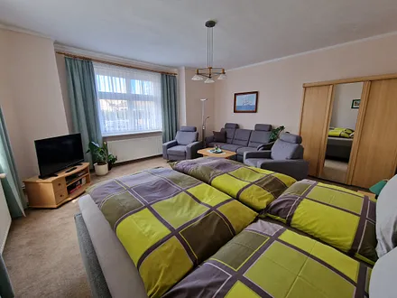 Wohn- und Schlafraum mit Doppelbett, Couch u. Sessel und Flach-TV