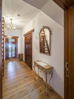 Flur mit Eingangstür. Hinter der Dekotreppe kommt man durch den begehbaren Kleiderschrank ins Bad 