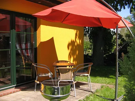 Terrasse mit Säulengrill, Sonnenschirm und Terrassenfeuer für kühle Sommerabende.