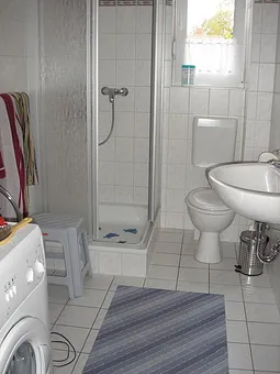 Badezimmer mit Dusche und Münzwaschmaschine