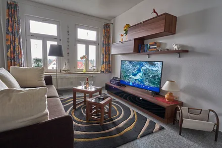 Wohnzimmer mit großem Sat-TV und etwas Ostseeblick in der laublosen Zeit