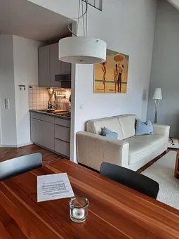 Küchenzeile und Wohn- und Essbereich mit Ledersofa und Teakmöbel