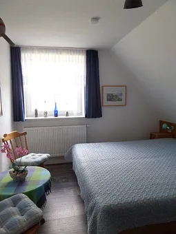 blaues Schlafzimmer mit kleiner Sitzgelegenheit