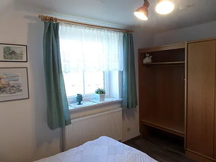 grünes Schlafzimmer mit Schrank und hellem Fenster