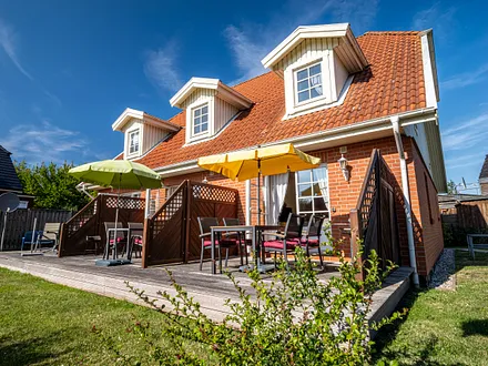 Ferienhaus Residenz zu den 3 Tannen Zingst - Aussenansicht rechter Reihenendhausteil mit Terrasse, Gartenmöbeln, großer Wiese und einer Schaukel für die kleinen Gäste