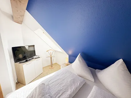 Schlafzimmer mit Doppelbett und Smart-TV