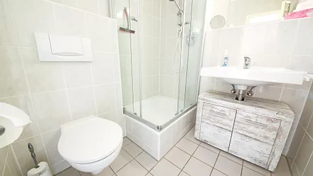 Modernes Bad mit Fenster, Dusche/WC und Handtuchtrocknerheizkörper.