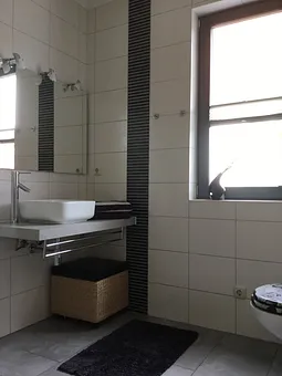 Das Badezimmer mit Waschplatz, großer  Echtglasdusche und WC