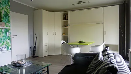 Blick über das Sofa auf 2Raumwunder-Schrankwand / Doppelbett eingeklappt und Eßtisch hochgefahren