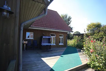 Holzterrasse mit Ostseeblick, Holzkohlegrill, Gartentisch mit 2 Gartenstühlen und einem Strandkorb.