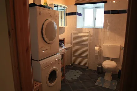 Badezimmer, linke Seite mit Waschbecken, Toilette, Waschmaschine und Wäschetrockner