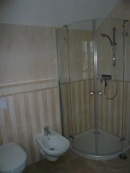 Bad im Schlafgeschoss mit Waschbecken, Ganzglasdusche, Toilette, Fußbodenheizung, Handtuchheizkörper und Außenfenster (nicht zu sehen) mit Fliegengitter