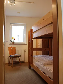 Im kleinen Zimmer steht ein stabiles Etagenbett mit verstellbaren Lattenrosten, separate Leselampen, eine Kommode