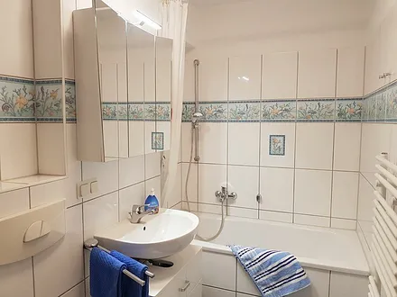 Maritimes Badezimmer mit Badewanne und Duscheinrichtung