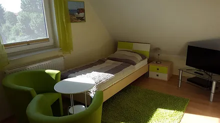 Schlafzimmer mit zwei Einzelbetten, TV und kleiner Stereoanlage im DG