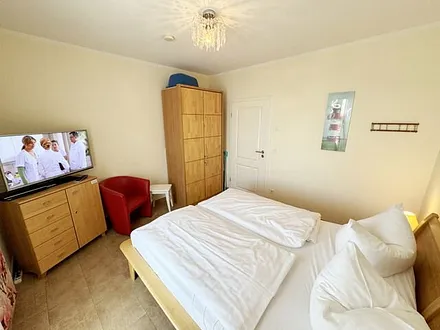 Schlafzimmer mit Doppelbett (2x 0,80 m x 2,00 m), Kleiderschrank, Wäschekommode, Sessel und LED-TV mit DVD