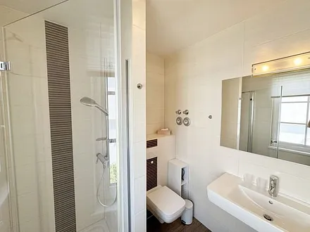 Badezimmer mit Dusche, WC, Waschbecken, Kosmetikspiegel, Handtuchwärmeheizkörper und Fön