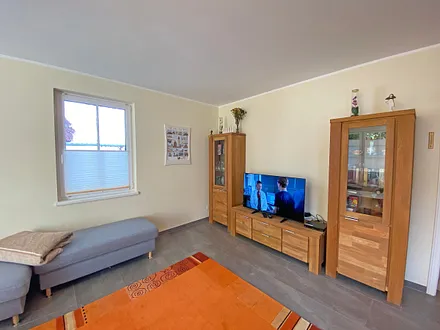 Wohnzimmer mit gemütlicher Eck- Couch mit Hocker, Couchtisch, Stehlampe, zwei Vitrinen, TV-Board mit Flachbild-TV sowie DVD-Player und CD-Player