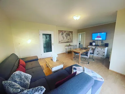 Wohnbereich mit Esstisch, Sofa, Flat TV, DVD Player und Zugang zur Terrasse, welche zur Tagessonne ausgerichtet ist.