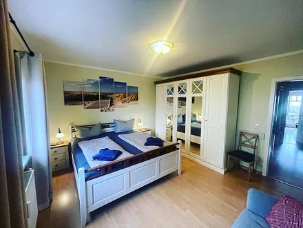 Schlafzimmer ist mit Doppelbett, Kleiderschrank und zusätzlichem Sofa ausgestattet und Flat TV an der Wand angebracht.