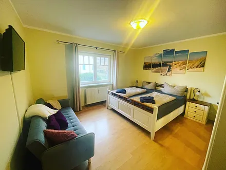 Schlafzimmer ist mit Doppelbett, Kleiderschrank und zusätzlichem Sofa ausgestattet.