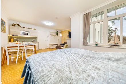 Das Fenster blickt Richtung Strandpromenade. Sie schauen auf die Düne, dahinter liegt das Meer.