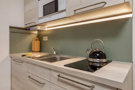 Die Küchenzeile ist ausgestattet mit Mikrowelle, Kühlschrank mit Eisfach, Induktionskochfeld mit passendem Kochgeschirr, Kaffeemaschine, Wasserkocher und Toaster.