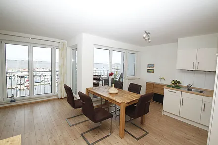 Koch-Essbereich mit Backofen und Geschirrspüler, daneben Balkon mit Panoramablick auf´s Wasser