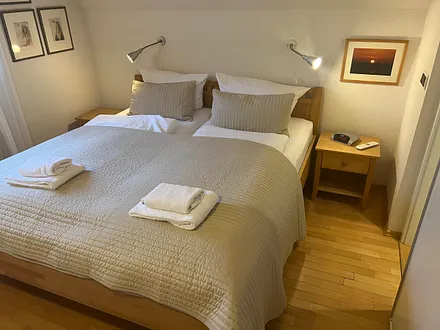 Schlafzimmer mit Naturholzbett und einer Ferderkernmatratze , TV zum abendlichen Abtauchen, direkter Zugang zum Badezimmer, Insektenschutz vor dem Fenster