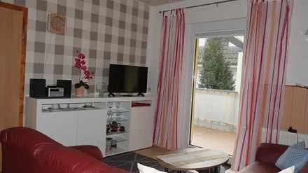 Wohnbereich mit TV, Couch und Blick auf die Terrasse.