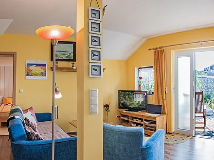 Wohnbereich mit Couch, TV und Blick auf die Terrasse.