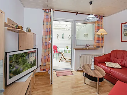 Wohnbereich mit TV und Blick auf die Terrasse.