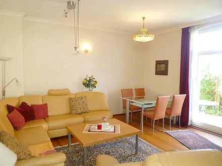 Wohnzimmer mit hochwertiger Ledergarnitur, besonderes Ambiente dank schöner Original-Holzböden, Kassettentüren und höherer Räume