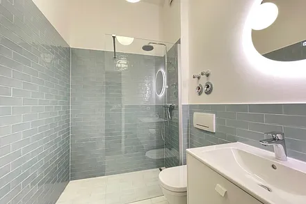 Das moderne Bad mit bodengleicher Dusche, WC und Waschtisch.