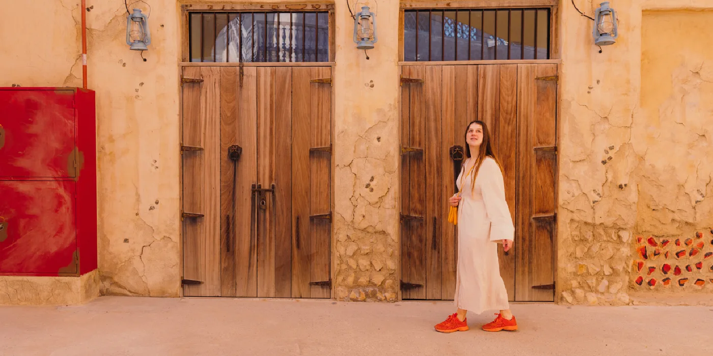 Woman in Arabian dress walking through Al Bastakiya’s historic streets in Dubai.