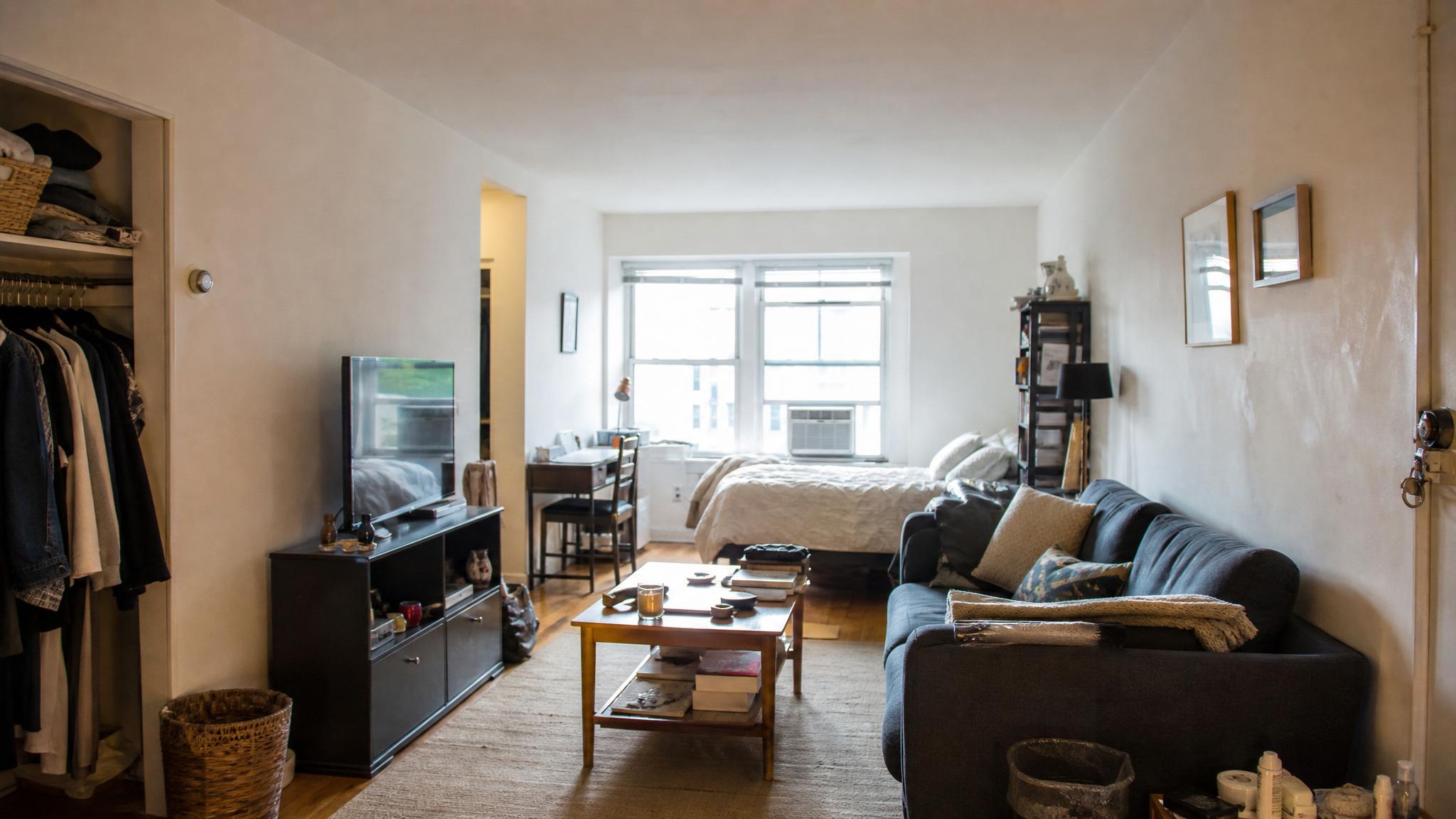 Before image of a small, cluttered studio apartment living room.