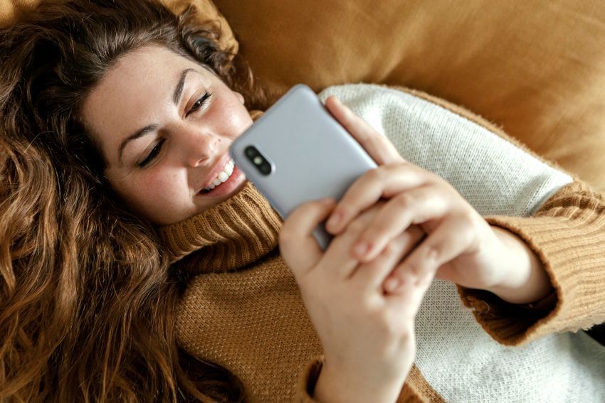 mujer joven tumbada mirando movil redes sociales