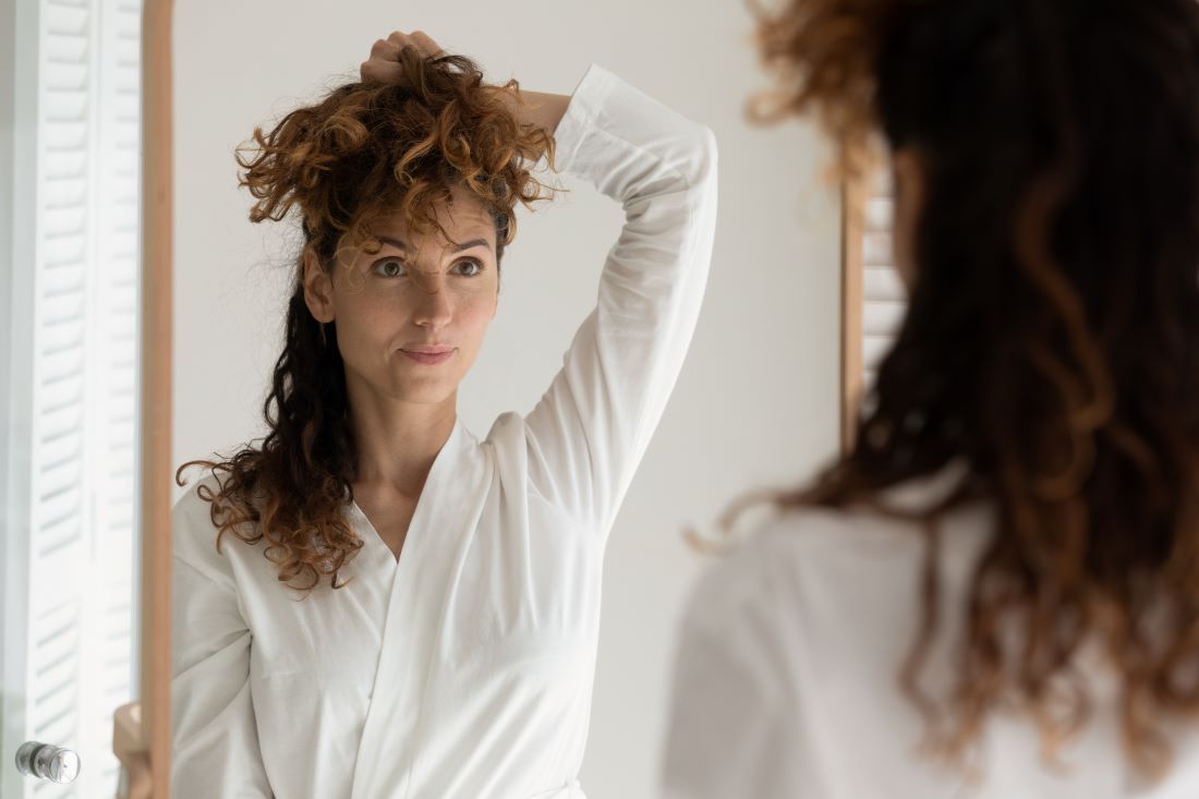 mujer pelo rizado mirandose espejo piel 