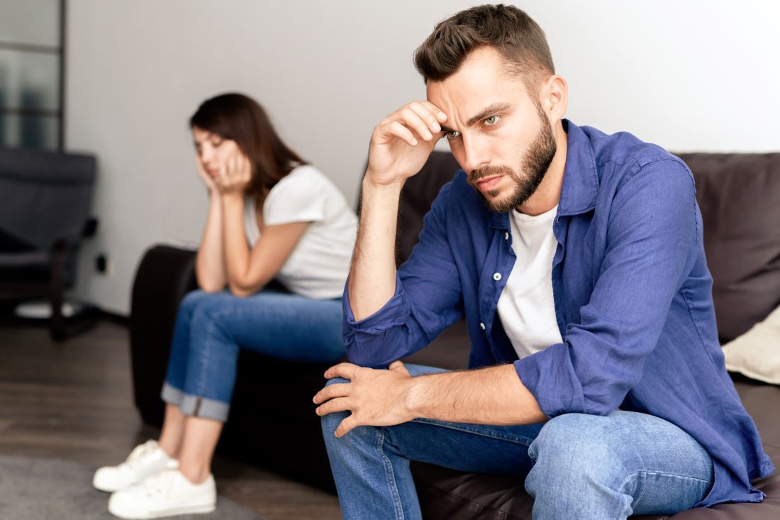 hombre mujer sentados sofa preocupados crisis pareja
