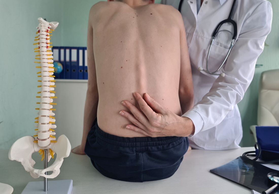 traumatologo examina columna vertebral paciente sentado mesa escoliosis