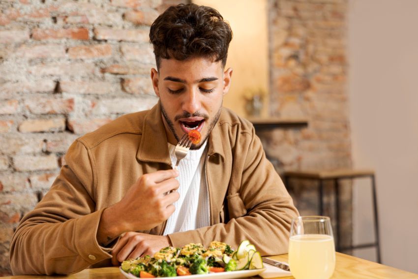 hombre joven barba chaqueta marron comiendo ensalada 