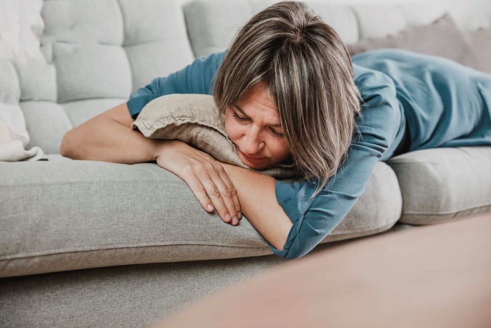 mujer pijama azul estirada sofa cansancio