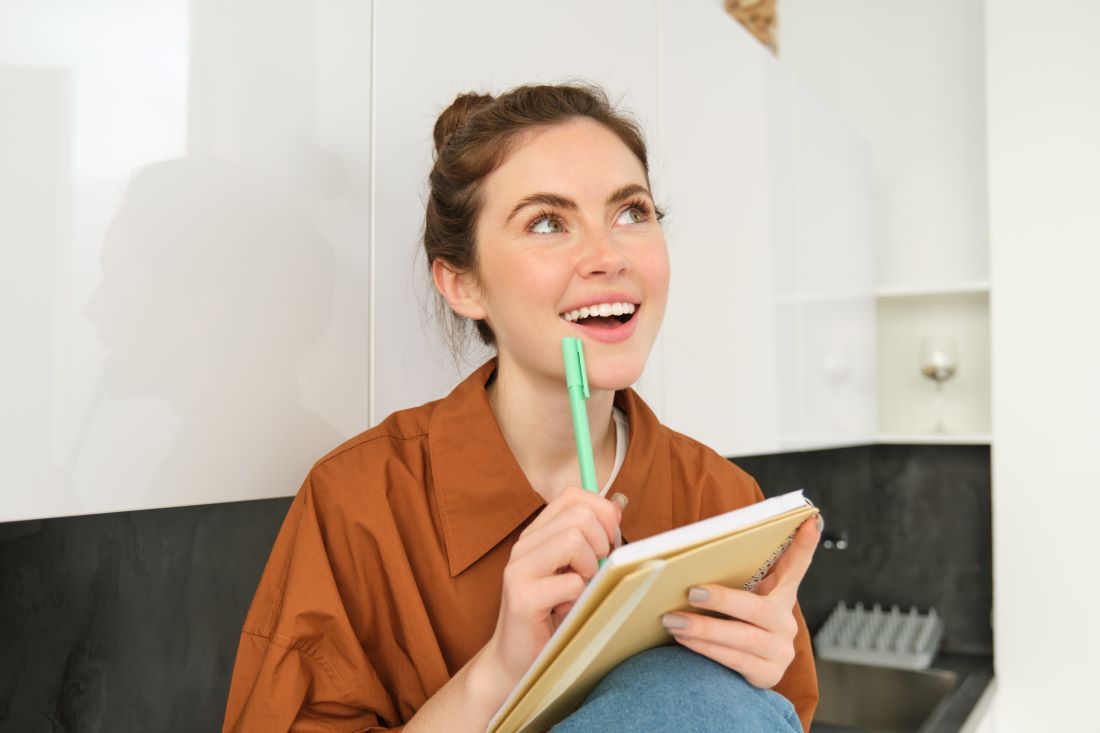 mujer pensativa feliz sonrie cuaderno mano boligrad