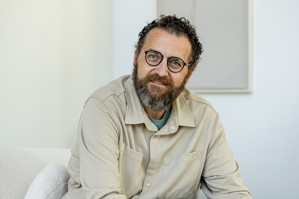 Foto eines dunkelhaarigen bärtigen Mannes mit dunkler Brille.