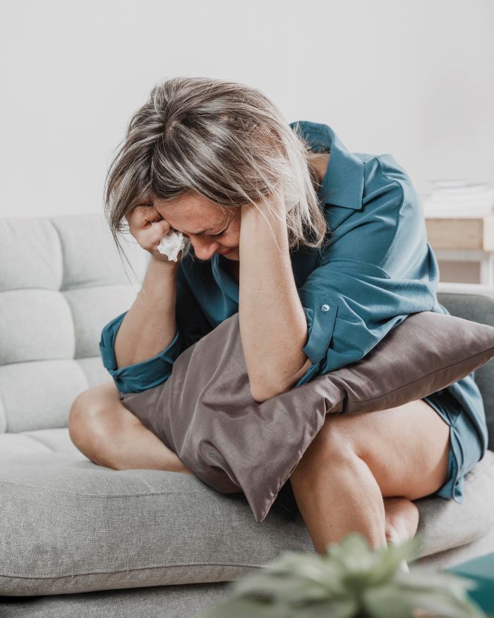 mulher adulta sentada sofá mãos na cabeça