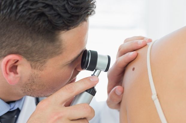 médico inspecionando a lesão de pele de um paciente