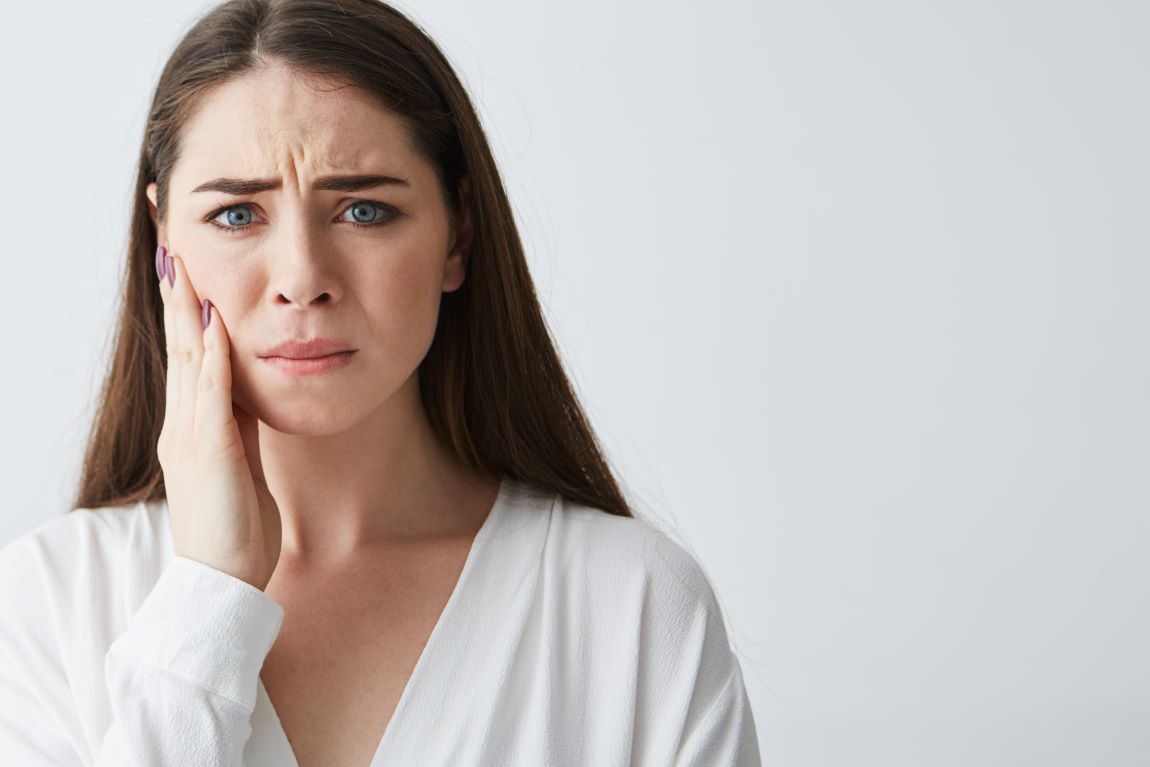 mujer camisa blanca mano mandibula dolor