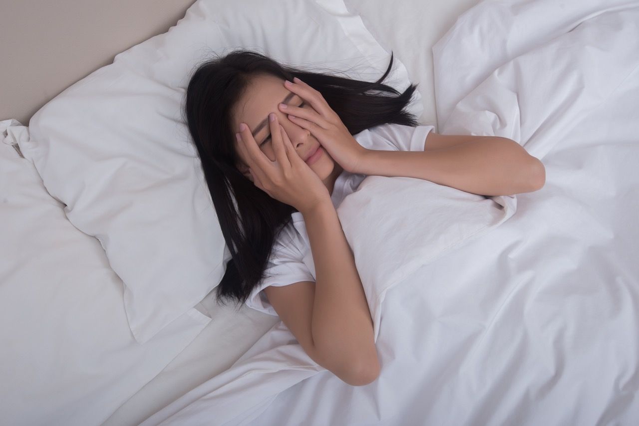 mujer tumbada cama sabanas blancas insomnio